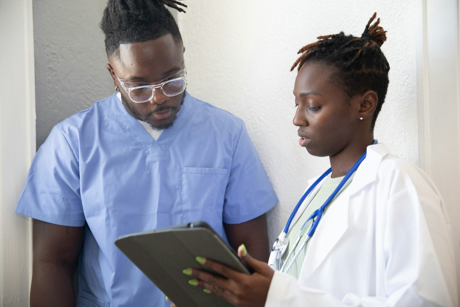 Two clinicians in a corridor looking at a tablet together