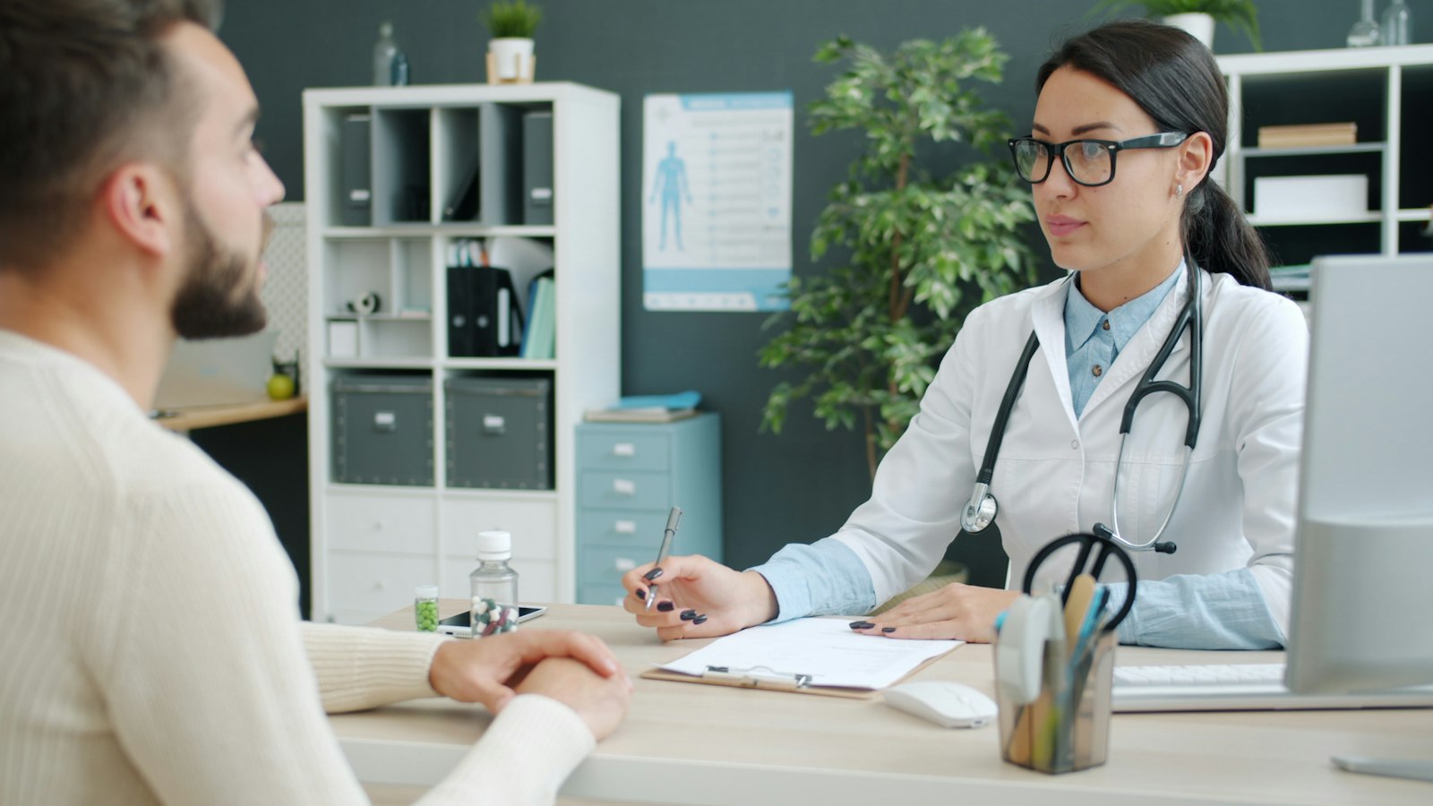 A doctor at her desk talking with a patient in a bright consulting room